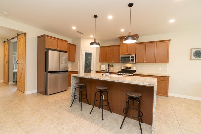 385 Fir St W, Madera, CA 93636 - kitchen with appliances with stainless steel finishes, a sink, a kitchen breakfast bar, brown cabinets, and a kitchen island with sink