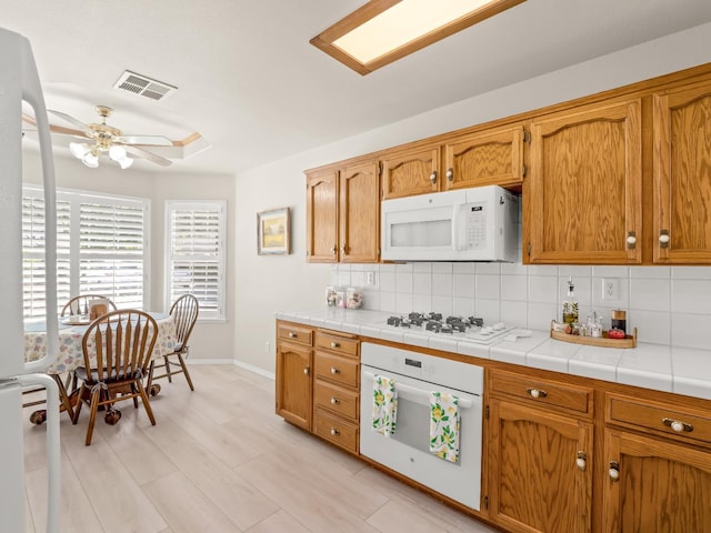 6424 N Allison Ln, Fresno, CA 93711 - kitchen featuring white appliances, tasteful backsplash, a ceiling fan, baseboards, and brown cabinetry