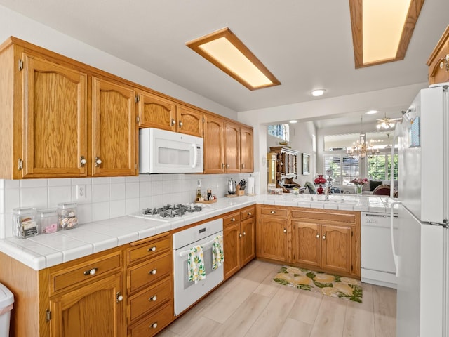 6424 N Allison Ln, Fresno, CA 93711 - kitchen featuring white appliances, decorative backsplash, brown cabinetry, a chandelier, and a peninsula