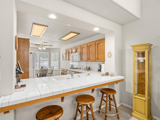 6424 N Allison Ln, Fresno, CA 93711 - kitchen featuring backsplash, a sink, white microwave, baseboards, and a kitchen breakfast bar