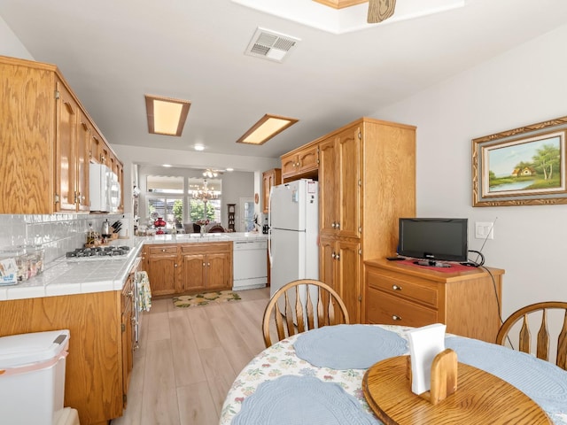 6424 N Allison Ln, Fresno, CA 93711 - kitchen with white appliances, tile countertops, light wood-style flooring, a peninsula, and decorative backsplash
