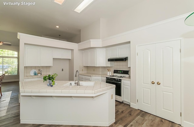 1783 E Pryor Dr, Fresno, CA 93720 - kitchen with gas range oven, a sink, under cabinet range hood, white cabinets, and recessed lighting