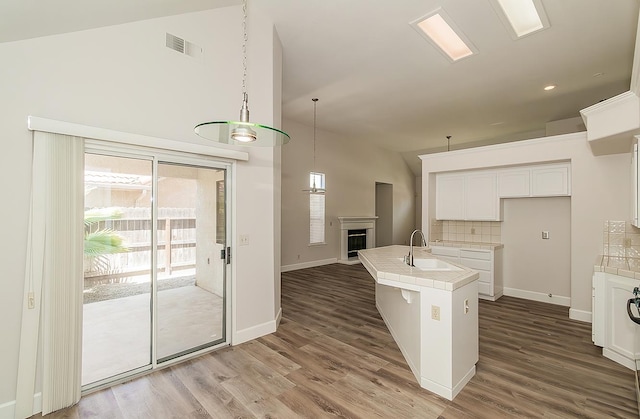 1783 E Pryor Dr, Fresno, CA 93720 - kitchen featuring a sink, tile counters, a kitchen island with sink, tasteful backsplash, and wood finished floors
