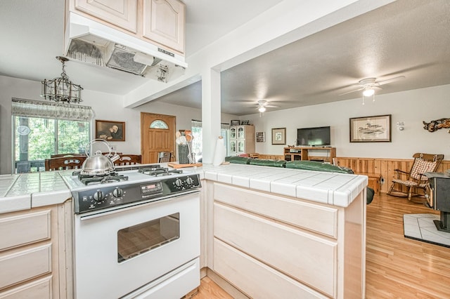 42357 Hanging Branch Rd, Shaver Lake, CA 93664 - kitchen featuring white gas stove, ceiling fan, under cabinet range hood, open floor plan, and tile counters