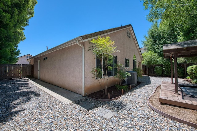 7518 N Trellis Cir, Fresno, CA 93720 - view of side of property featuring stucco siding, central air condition unit, a fenced backyard, and a deck