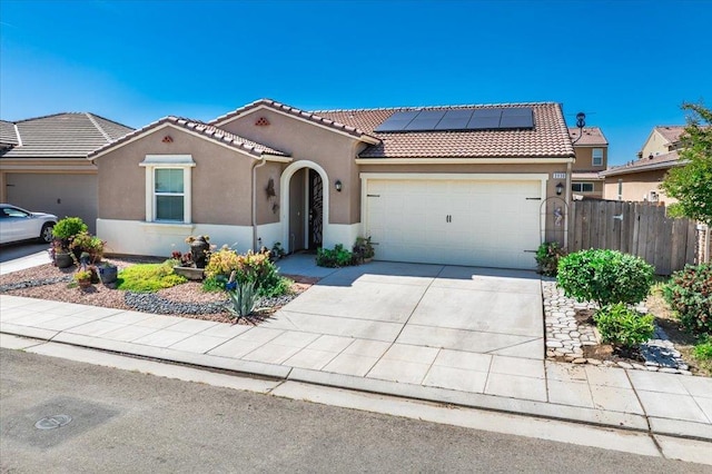3930 Saginaw Ave, Clovis, CA 93619 - mediterranean / spanish home featuring an attached garage, stucco siding, a tiled roof, and roof mounted solar panels