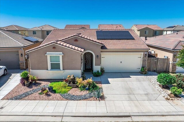 3930 Saginaw Ave, Clovis, CA 93619 - view of front of house featuring stucco siding, a tile roof, a garage, roof mounted solar panels, and concrete driveway
