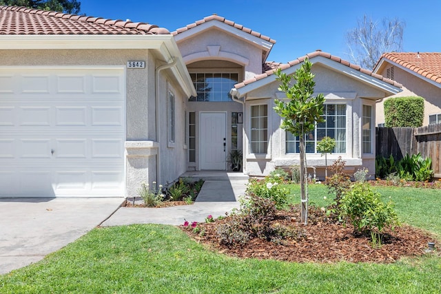 5642 W Beechwood Ave, Fresno, CA 93722 - view of front of home featuring a garage, a tiled roof, and stucco siding