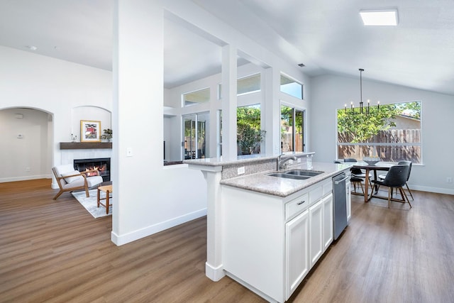 5642 W Beechwood Ave, Fresno, CA 93722 - kitchen featuring a sink, stainless steel dishwasher, healthy amount of natural light, a glass covered fireplace, and lofted ceiling