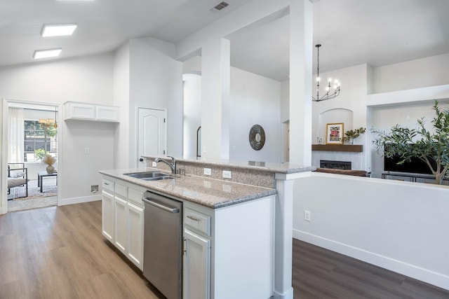 5642 W Beechwood Ave, Fresno, CA 93722 - kitchen with stainless steel dishwasher, a sink, white cabinets, a fireplace, and wood finished floors