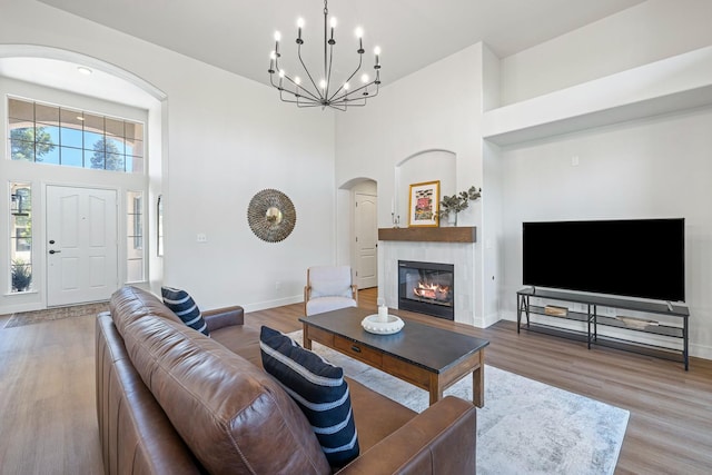 5642 W Beechwood Ave, Fresno, CA 93722 - living area featuring arched walkways, a towering ceiling, a glass covered fireplace, wood finished floors, and a chandelier