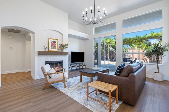 5642 W Beechwood Ave, Fresno, CA 93722 - living area with a high ceiling, wood finished floors, baseboards, a glass covered fireplace, and arched walkways