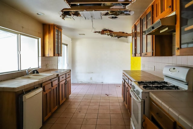 1315 W Fedora Ave, Fresno, CA 93705 - kitchen featuring white appliances, tile countertops, wall chimney range hood, brown cabinets, and decorative backsplash