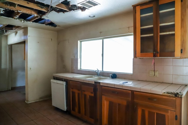 1315 W Fedora Ave, Fresno, CA 93705 - kitchen featuring dishwasher, tile counters, decorative backsplash, brown cabinetry, and light tile patterned flooring