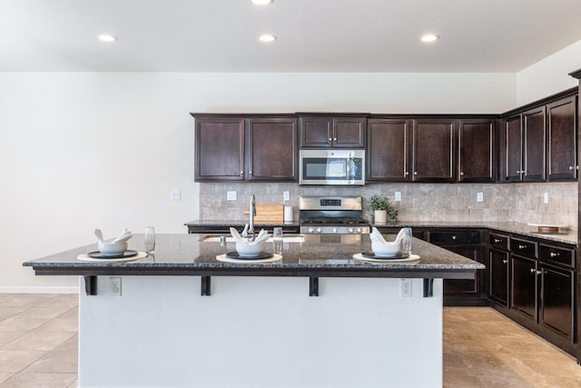 3834 Sussex Ave, Clovis, CA 93619 - kitchen featuring stainless steel appliances, a breakfast bar area, dark stone countertops, decorative backsplash, and recessed lighting