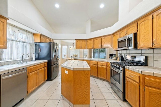 2903 Desert Ranch Way, Madera, CA 93637 - kitchen with stainless steel appliances, a peninsula, a sink, tile countertops, and tasteful backsplash