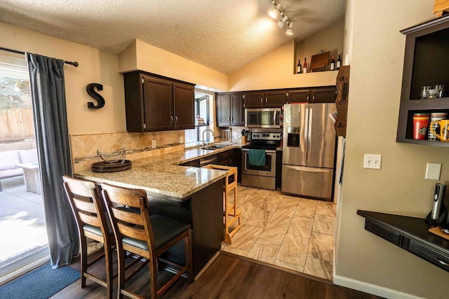 1603 E Serena Ave, Fresno, CA 93720 - kitchen featuring stainless steel appliances, a peninsula, a textured ceiling, dark brown cabinets, and plenty of natural light
