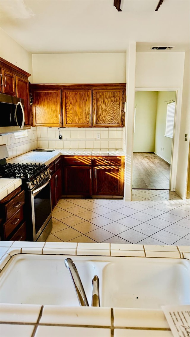 5346 W Flint Way, Fresno, CA 93722 - kitchen featuring stainless steel appliances, tile countertops, decorative backsplash, and light tile patterned floors