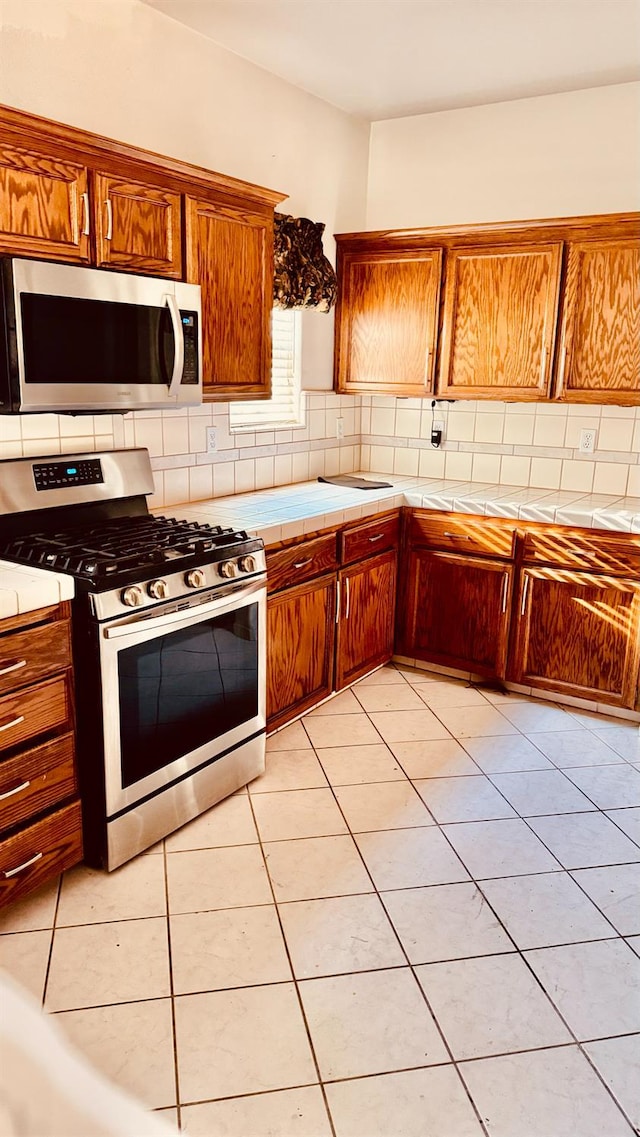 5346 W Flint Way, Fresno, CA 93722 - kitchen with appliances with stainless steel finishes, tile counters, decorative backsplash, and brown cabinets