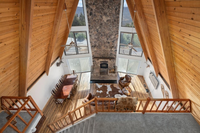 38303 Woodland Rd, Shaver Lake, CA 93664 - carpeted living room featuring ceiling fan, healthy amount of natural light, a stone fireplace, a high ceiling, and wooden walls