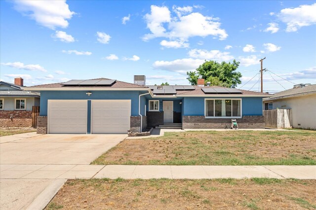 4003 E Fedora Ave, Fresno, CA 93726 - view of front of home with brick siding, a garage, solar panels, concrete driveway, and stucco siding