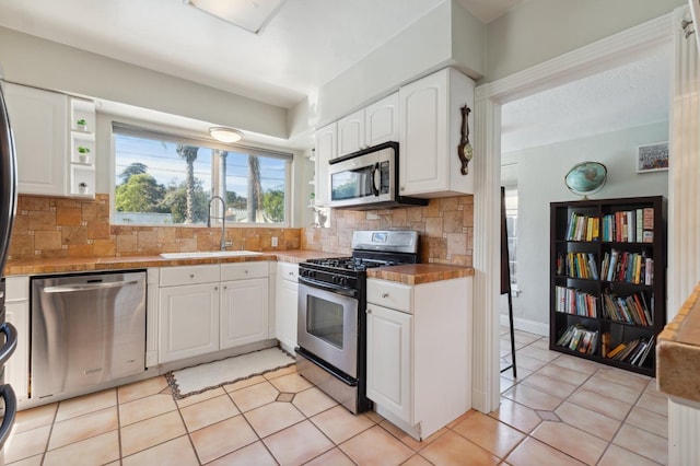 315 E Clinton Ave, Fresno, CA 93704 - kitchen with appliances with stainless steel finishes, a sink, white cabinets, backsplash, and light tile patterned flooring