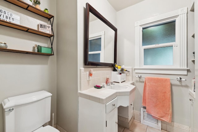315 E Clinton Ave, Fresno, CA 93704 - half bathroom featuring toilet, vanity, tile patterned floors, tasteful backsplash, and baseboards