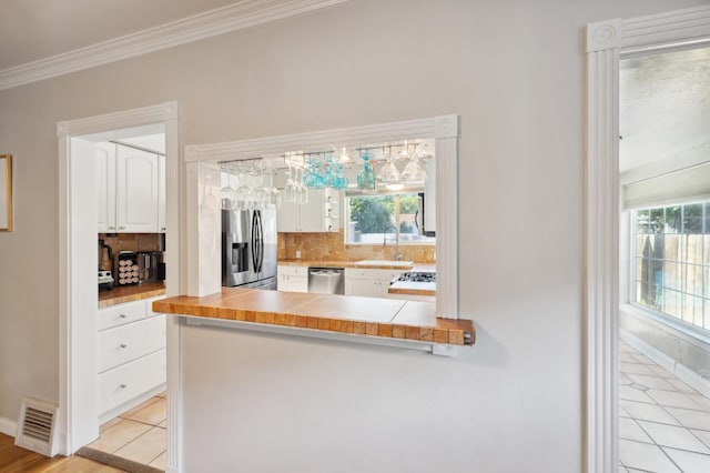 315 E Clinton Ave, Fresno, CA 93704 - kitchen featuring appliances with stainless steel finishes, a sink, white cabinets, decorative backsplash, and crown molding