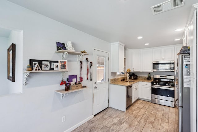 119 Magnolia Ave, Lemoore, CA 93245 - kitchen featuring stainless steel appliances, a sink, white cabinets, light wood-style flooring, and light stone counters