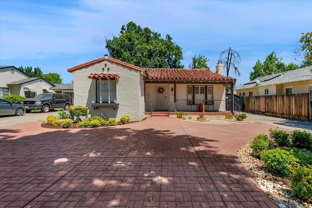 739 E Harvard Ave, Fresno, CA 93704 - mediterranean / spanish home featuring a porch, a tiled roof, stucco siding, and a chimney