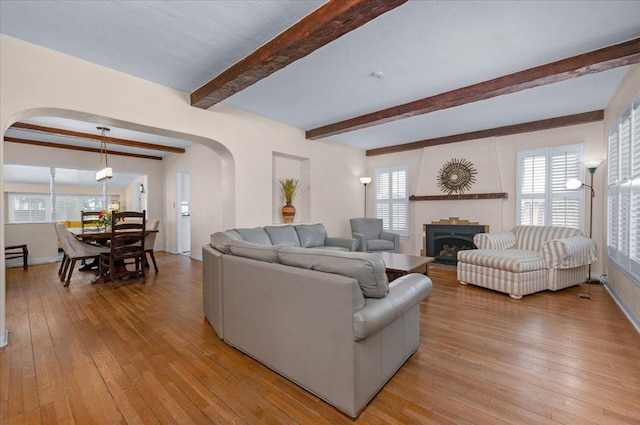 739 E Harvard Ave, Fresno, CA 93704 - living room featuring arched walkways, light wood finished floors, beamed ceiling, a fireplace, and baseboards