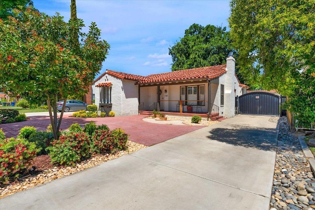 739 E Harvard Ave, Fresno, CA 93704 - mediterranean / spanish-style house featuring decorative driveway, stucco siding, a porch, a tile roof, and a gate