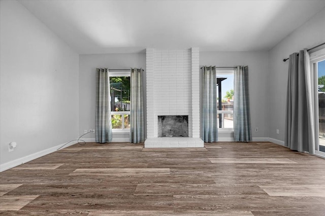 6569 N Kennedy Ave, Fresno, CA 93710 - unfurnished living room featuring wood finished floors, a brick fireplace, and baseboards