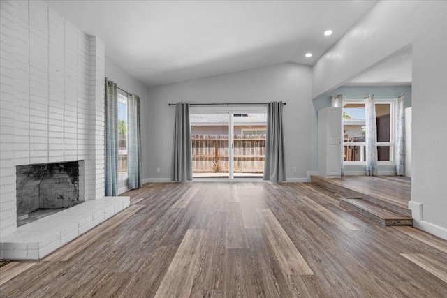 6569 N Kennedy Ave, Fresno, CA 93710 - unfurnished living room with wood finished floors, a brick fireplace, vaulted ceiling, recessed lighting, and baseboards