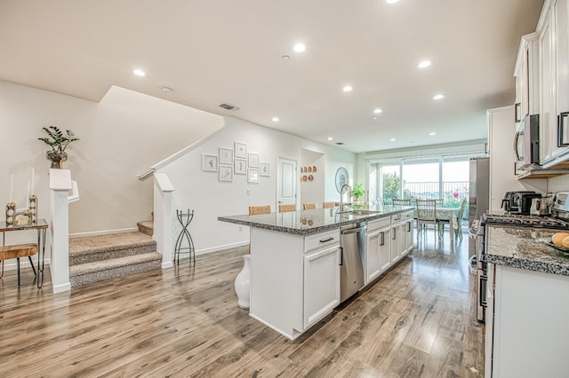 4284 Hillside Rd, Madera, CA 93636 - kitchen with stainless steel appliances, an island with sink, white cabinets, a sink, and light wood finished floors