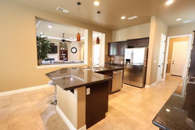 3309 Beverly Ave, Clovis, CA 93619 - kitchen featuring appliances with stainless steel finishes, light tile patterned floors, a kitchen island with sink, hanging light fixtures, and recessed lighting
