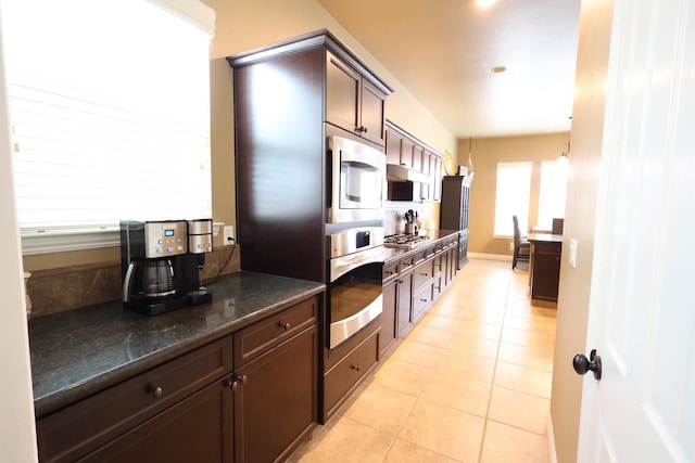 3309 Beverly Ave, Clovis, CA 93619 - kitchen with appliances with stainless steel finishes, light tile patterned floors, dark brown cabinetry, and dark stone countertops