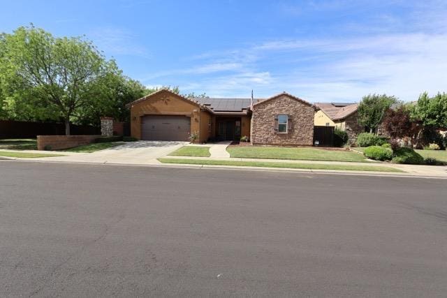 3309 Beverly Ave, Clovis, CA 93619 - ranch-style house featuring an attached garage, solar panels, concrete driveway, stone siding, and a front yard