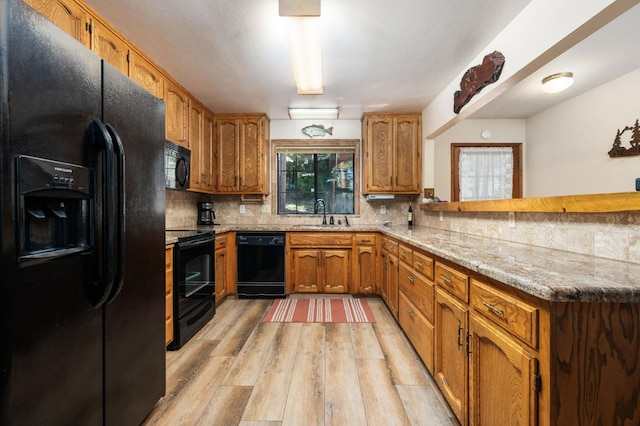 40758 Cold Springs Ln, Shaver Lake, CA 93664 - kitchen with black appliances, a peninsula, light wood-style floors, brown cabinets, and tasteful backsplash