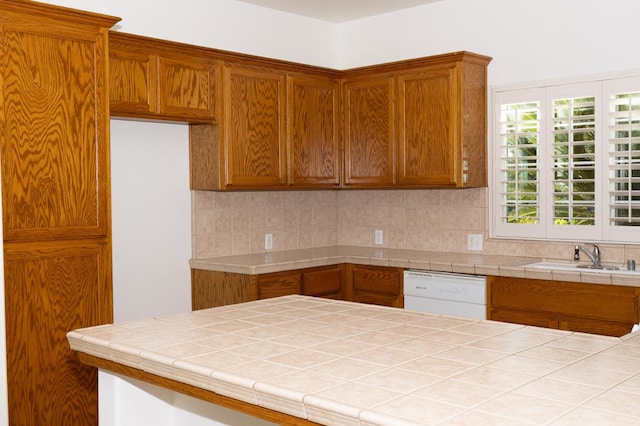 2300 Sierra Ave Unit 129, Kingsburg, CA 93631 - kitchen with white dishwasher, a sink, backsplash, brown cabinetry, and tile counters