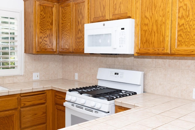 2300 Sierra Ave Unit 129, Kingsburg, CA 93631 - kitchen with white appliances, backsplash, brown cabinetry, and tile countertops