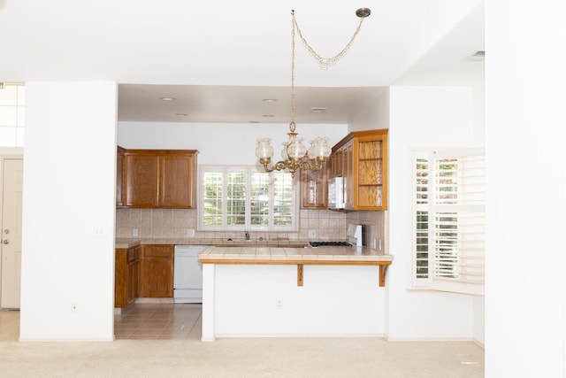 2300 Sierra Ave Unit 129, Kingsburg, CA 93631 - kitchen with white appliances, tile counters, a chandelier, a peninsula, and brown cabinetry