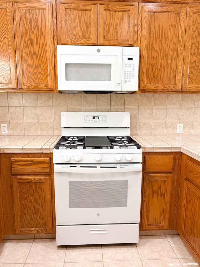 2300 Sierra Ave Unit 129, Kingsburg, CA 93631 - kitchen with white appliances, tile counters, and decorative backsplash