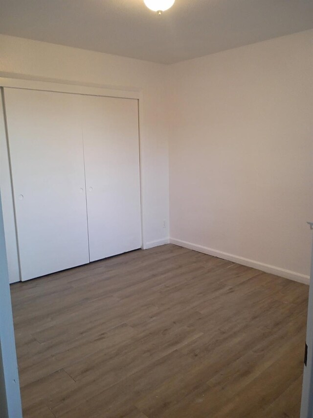 3332 W Shields Ave Unit 101, Fresno, CA 93722 - unfurnished bedroom with a closet, dark wood-style flooring, and baseboards