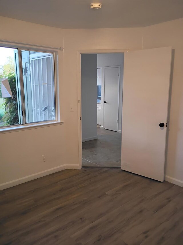 3332 W Shields Ave Unit 101, Fresno, CA 93722 - unfurnished bedroom with baseboards and dark wood-style flooring