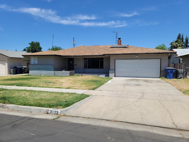3023 E Robinson Ave, Fresno, CA 93726 - ranch-style house with solar panels, driveway, an attached garage, a front yard, and stucco siding