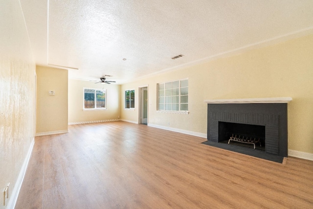 2744 E Michigan Ave, Fresno, CA 93703 - unfurnished living room featuring wood finished floors, a textured ceiling, a fireplace, ceiling fan, and baseboards