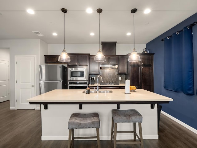 6053 E Brick Dr, Fresno, CA 93727 - kitchen with appliances with stainless steel finishes, dark wood-style flooring, backsplash, light countertops, and a kitchen bar