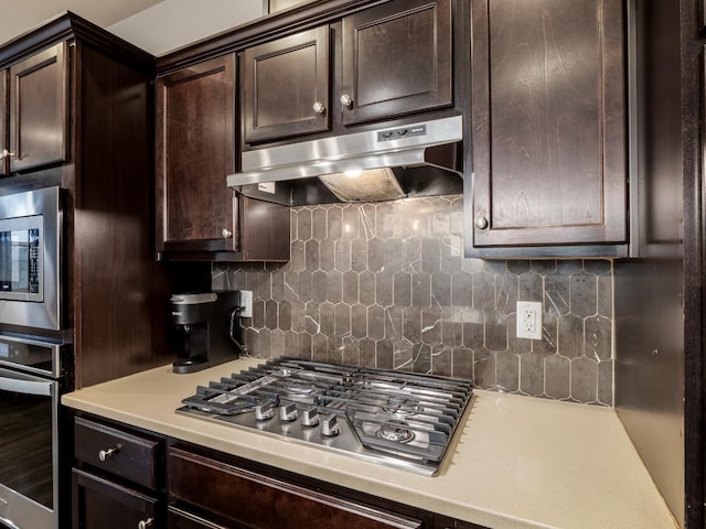 6053 E Brick Dr, Fresno, CA 93727 - kitchen with under cabinet range hood, stainless steel appliances, light countertops, dark brown cabinetry, and backsplash