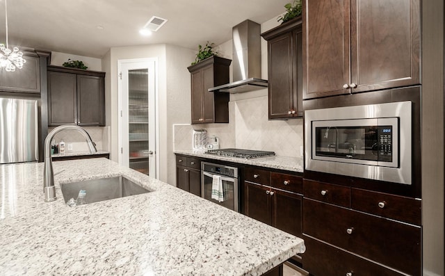 5615 N Lucy Ruiz Ave, Fresno, CA 93723 - kitchen featuring wall chimney exhaust hood, stainless steel appliances, a sink, dark brown cabinetry, and tasteful backsplash